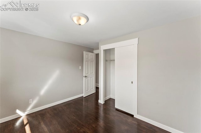 unfurnished bedroom with baseboards, dark wood finished floors, and a closet