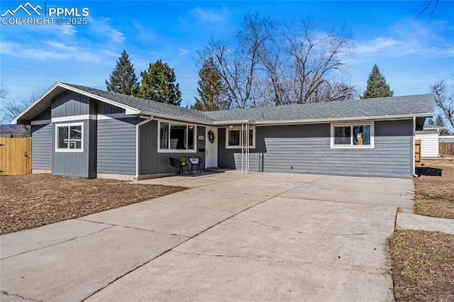 ranch-style house with a shingled roof, concrete driveway, and fence