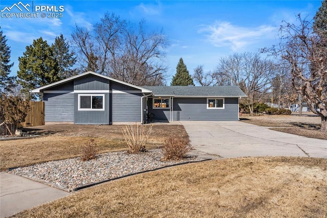 ranch-style home featuring concrete driveway and fence