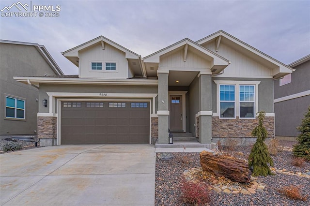 craftsman-style home with a garage, stone siding, and driveway