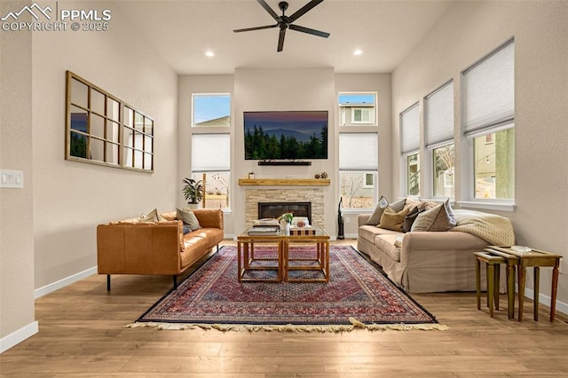 living area with a glass covered fireplace, baseboards, and hardwood / wood-style flooring