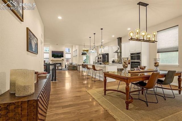 dining room featuring recessed lighting, a fireplace, baseboards, and wood finished floors