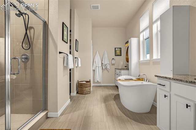 full bath featuring a stall shower, visible vents, a freestanding tub, and vanity