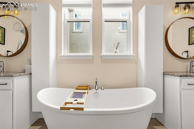 full bath featuring a freestanding tub and two vanities