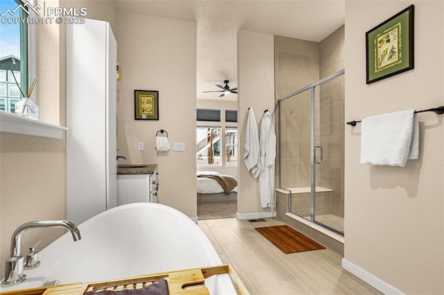 ensuite bathroom with a stall shower, baseboards, a ceiling fan, a soaking tub, and ensuite bath