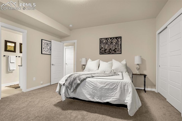 carpeted bedroom featuring ensuite bath and baseboards