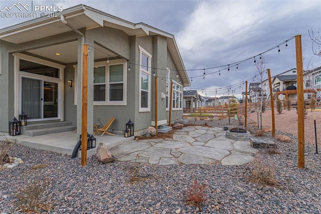 view of side of property with entry steps, an outdoor fire pit, a patio, and stucco siding