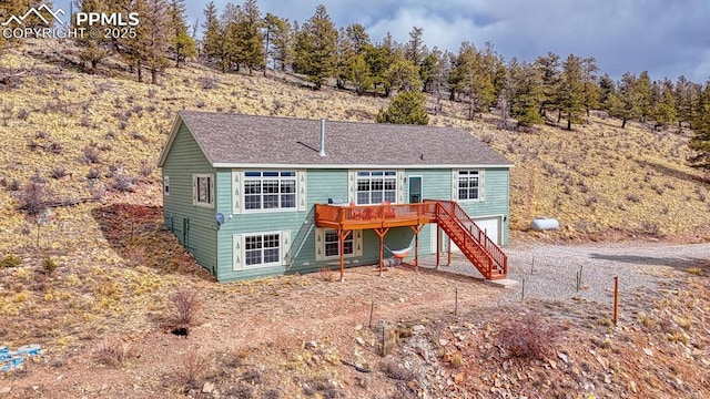 rear view of house with a deck, driveway, stairway, and a garage