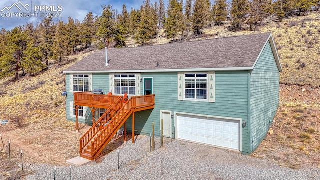 view of front facade featuring a garage, stairs, roof with shingles, a wooden deck, and gravel driveway