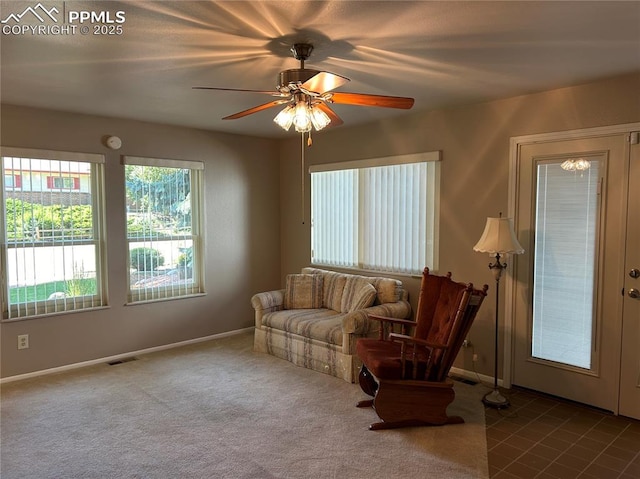 living area with a ceiling fan, visible vents, carpet floors, and baseboards