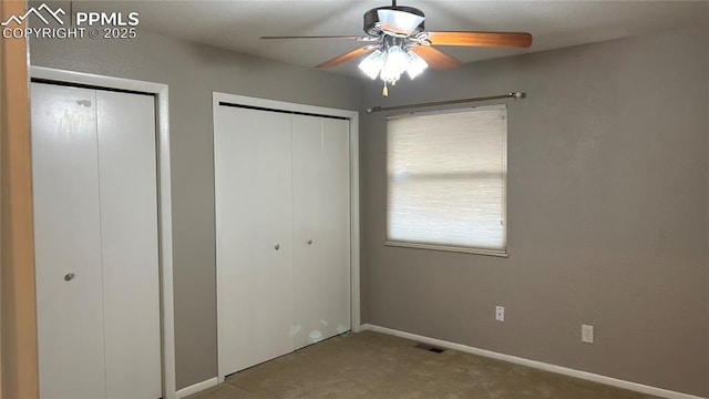 unfurnished bedroom featuring ceiling fan, two closets, baseboards, and carpet floors