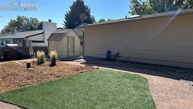 view of side of home featuring a storage shed, a yard, fence, and an outdoor structure