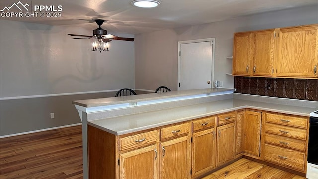 kitchen with a peninsula, light countertops, light wood-type flooring, and ceiling fan