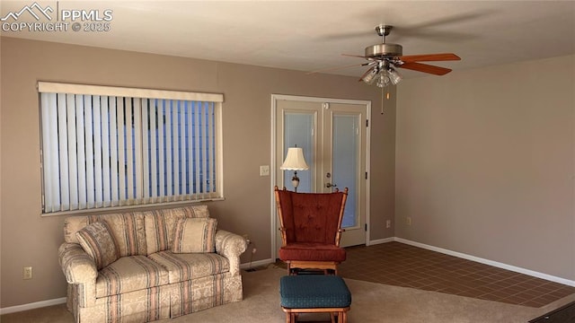 carpeted living area featuring baseboards and a ceiling fan