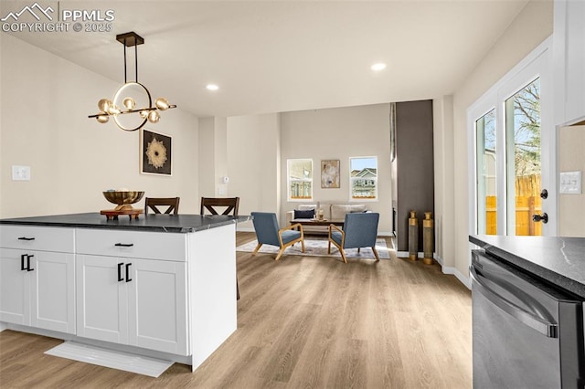 kitchen featuring dark countertops, plenty of natural light, white cabinets, light wood-type flooring, and dishwasher