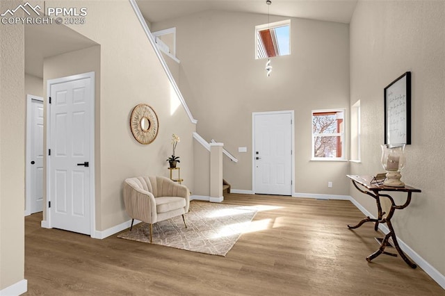 foyer entrance with high vaulted ceiling, a wealth of natural light, stairway, and wood finished floors