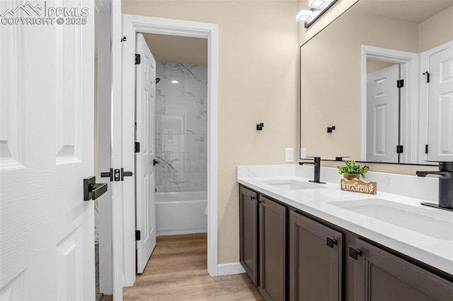 full bathroom with shower / bathtub combination, double vanity, wood finished floors, and a sink