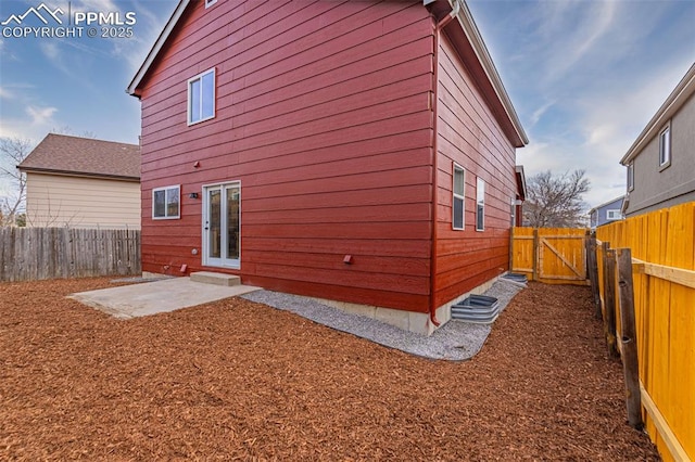 rear view of house featuring a fenced backyard, a gate, and a patio