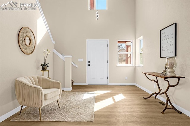 foyer featuring a towering ceiling, baseboards, stairway, and wood finished floors