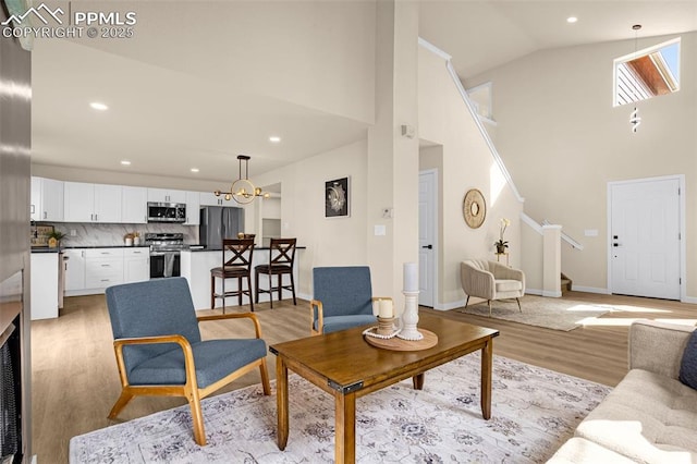 living room featuring recessed lighting, stairway, light wood-style floors, high vaulted ceiling, and baseboards