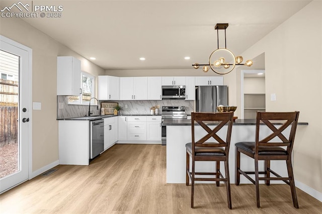 kitchen with appliances with stainless steel finishes, dark countertops, a sink, and a kitchen breakfast bar