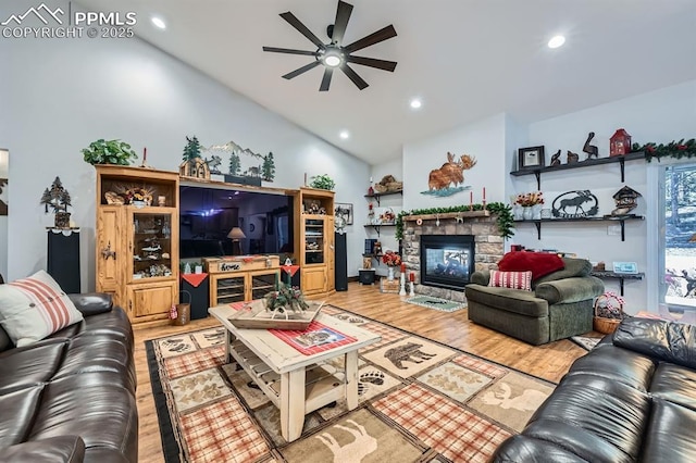 living room featuring ceiling fan, a stone fireplace, recessed lighting, wood finished floors, and vaulted ceiling