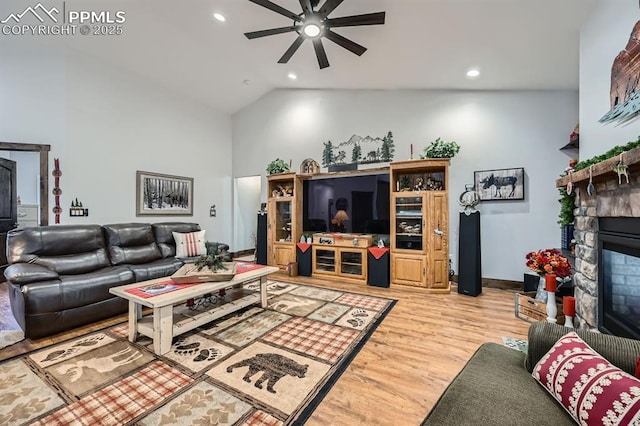 living room featuring light wood finished floors, ceiling fan, a stone fireplace, and recessed lighting