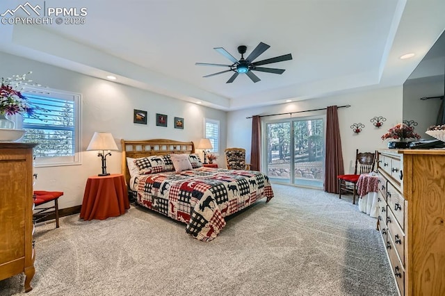 carpeted bedroom with ceiling fan, baseboards, a raised ceiling, and access to exterior