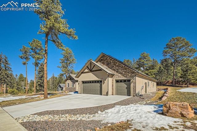 view of front of home featuring a garage, stone siding, driveway, and stucco siding