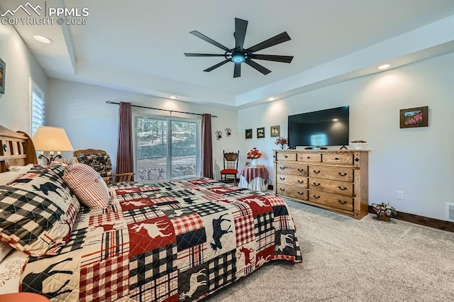 carpeted bedroom featuring a tray ceiling, multiple windows, and recessed lighting