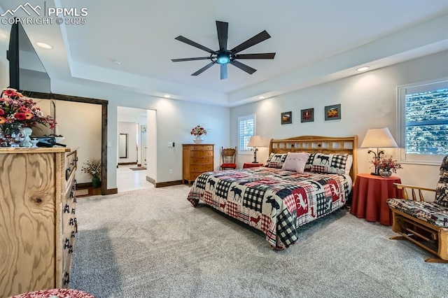 carpeted bedroom with ensuite bathroom, recessed lighting, a raised ceiling, and baseboards