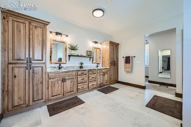 bathroom featuring a sink, baseboards, and double vanity