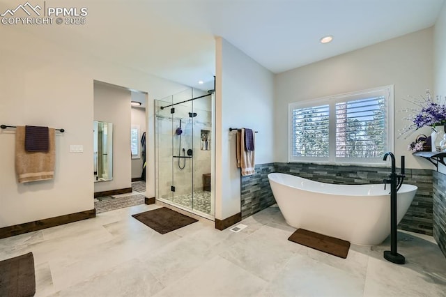 bathroom with a stall shower, wainscoting, a freestanding tub, tile walls, and recessed lighting