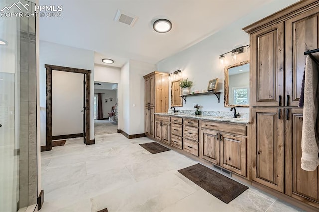 bathroom featuring visible vents, a sink, baseboards, and double vanity