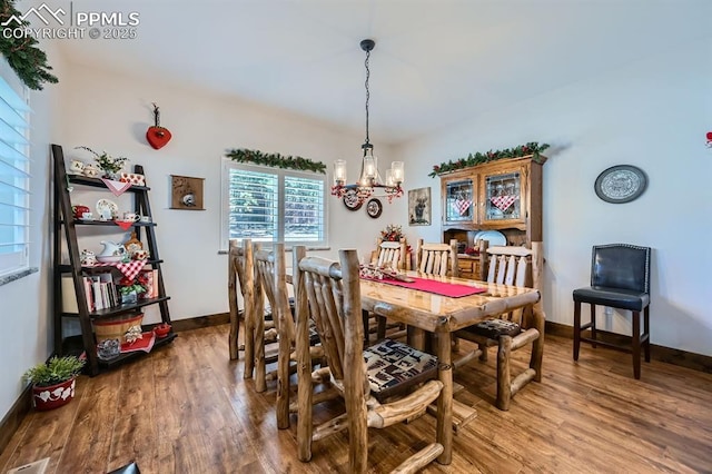 dining space with a chandelier, wood finished floors, and baseboards