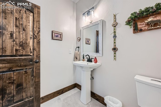 bathroom featuring tile patterned flooring, toilet, and baseboards