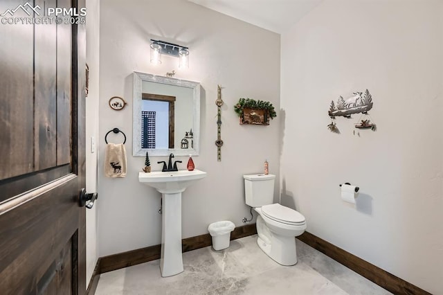 half bath featuring a sink, toilet, and baseboards