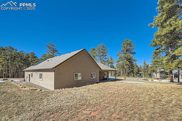 view of side of property with a yard and stucco siding