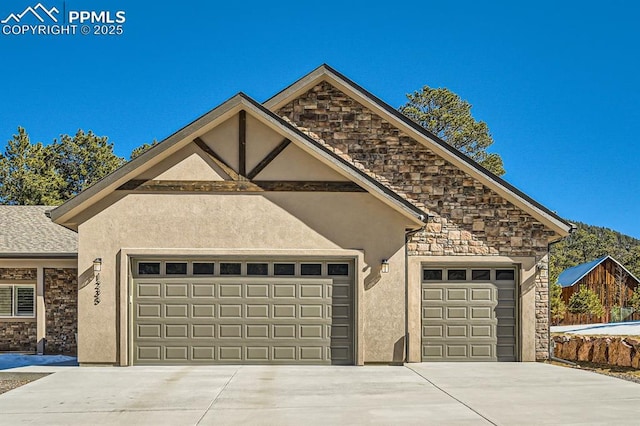 view of front of home featuring stone siding, an attached garage, driveway, and stucco siding