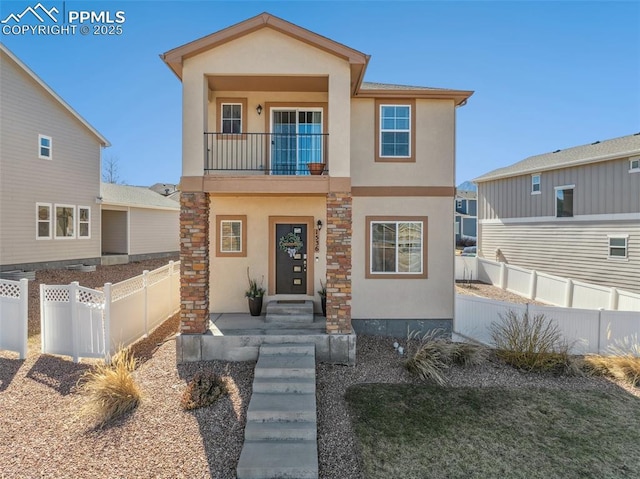 view of front of property featuring fence private yard, a balcony, and stucco siding