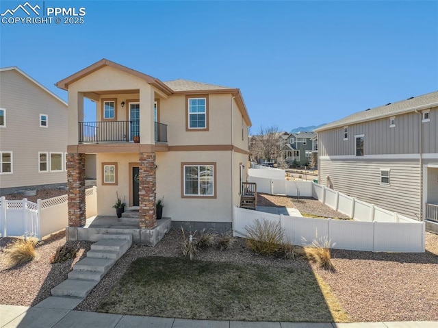 view of front of property with a residential view, a fenced backyard, a balcony, and stucco siding