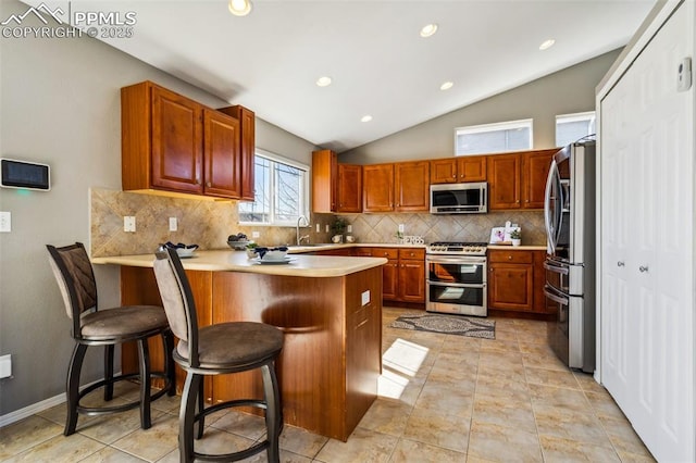 7619 High Gate Dr, Fountain, CO 80817 - kitchen with light countertops, backsplash, appliances with stainless steel finishes, vaulted ceiling, and a peninsula
