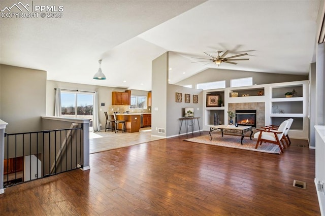 7619 High Gate Dr, Fountain, CO 80817 - living area featuring visible vents, a tiled fireplace, hardwood / wood-style flooring, ceiling fan, and vaulted ceiling