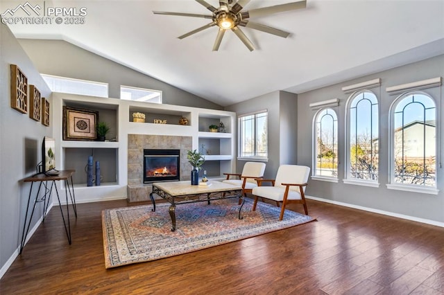 7619 High Gate Dr, Fountain, CO 80817 - living area with dark wood-style floors, built in shelves, a fireplace, vaulted ceiling, and baseboards