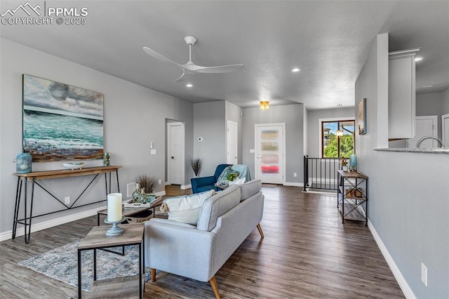 living room with ceiling fan, dark wood-type flooring, and baseboards