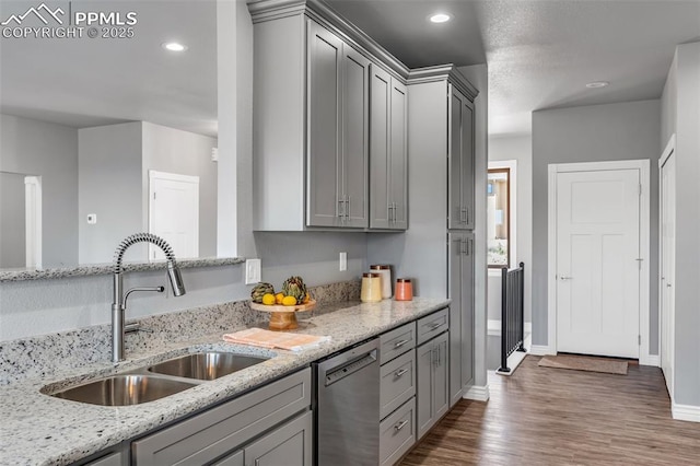 kitchen featuring recessed lighting, gray cabinets, stainless steel dishwasher, a sink, and wood finished floors