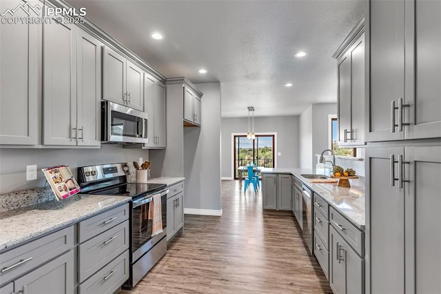 kitchen featuring recessed lighting, a sink, appliances with stainless steel finishes, gray cabinets, and light wood finished floors