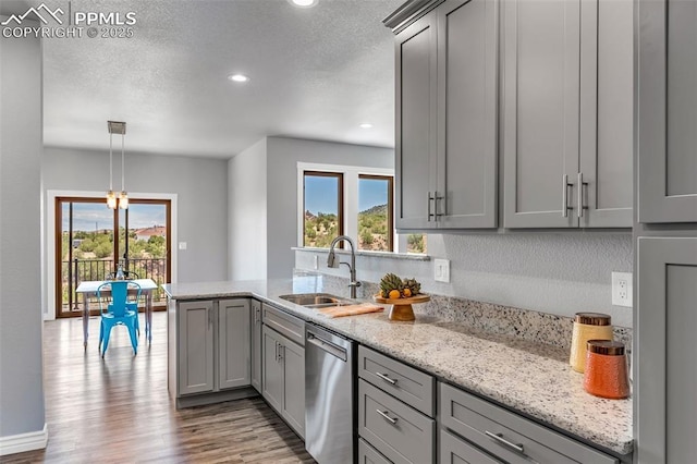 kitchen with dishwasher, wood finished floors, a peninsula, gray cabinetry, and a sink