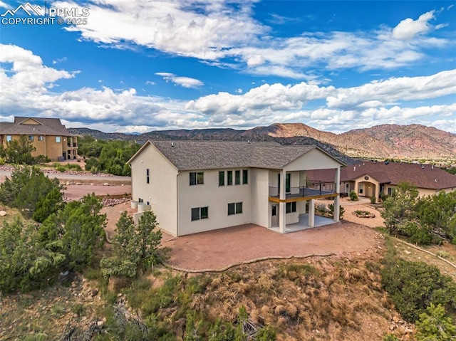 rear view of house featuring a patio area, a mountain view, and stucco siding