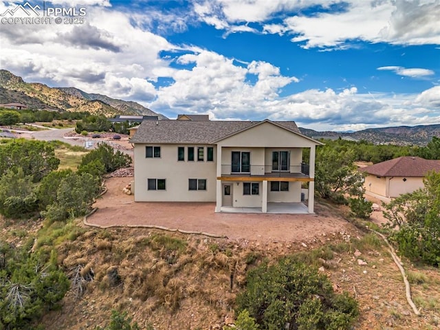 rear view of house featuring a patio area, a mountain view, a balcony, and stucco siding